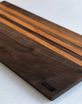 Long handcrafted walnut charcuterie board with cherry stripes called the Honky Tonk Highway board by Nash Boards