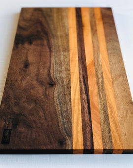 Long handcrafted walnut charcuterie board with cherry stripes called the Honky Tonk Highway board by Nash Boards