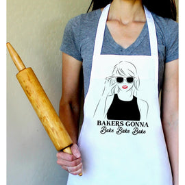 White cotton apron with “Bakers Gonna Bake Bake Bake” printed text, inspired by Taylor Swift lyrics, sized 34" x 27", perfect for baking and gifting.