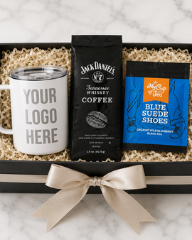 Gift set with a mug, coffee package, and tea package in a box on a marble surface.