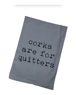 Grey flour-sack kitchen towel with the phrase “Corks Are For Quitters” printed in bold black text, folded and displayed for gift or kitchen use.