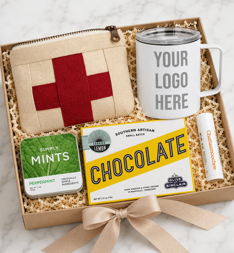 Gift set with mug, pouch, mints, and chocolate bar in a box on a marble surface.