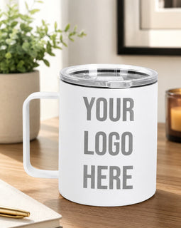 White mug with 'Your Logo Here' text on a wooden surface with a plant and candle in the background