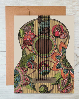 Greeting card featuring a colorful guitar illustration by Valentina Harper, blank inside, shown with a kraft envelope on a wooden surface.