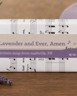 Bar of soap with music note design packaging on a wooden surface with lavender flowers.