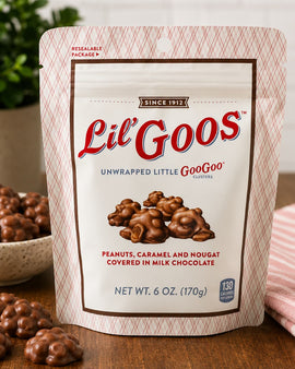 Packaging of Lil' Goos chocolate clusters with a bowl of clusters and a pink cloth in the background.