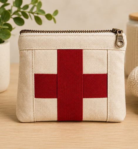 Small beige pouch with a red cross on a wooden surface