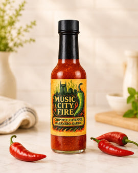 Bottle of Music City Fire hot sauce with chili peppers on a kitchen counter