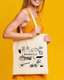 Person holding a tote bag with Nashville-themed illustrations on a yellow background