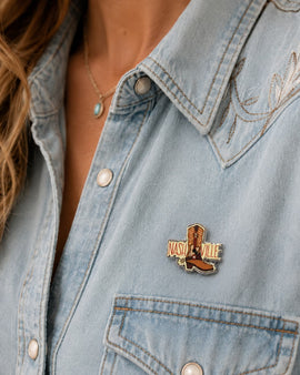 Denim jacket with a 'Nashville' pin featuring a cowboy boot.