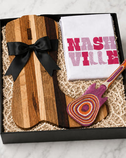 Gift set with wooden cutting board, towel, and guitar-shaped tool in a box.