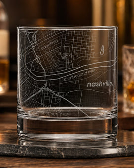 Clear glass with engraved map of Nashville on a wooden surface with blurred background