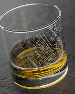 Clear glass with map design filled with yellow liquid on a dark surface