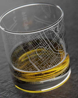 Clear glass with map design filled with yellow liquid on a dark surface