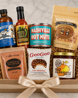 Assorted gift set with hot sauce, snack items, and a jar of jam in a box.