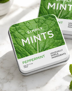 Tin of Simply Mints with mint leaves on a marble surface