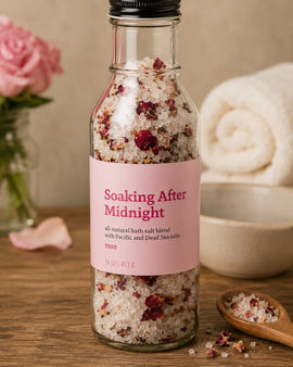 Bottle of 'Soaking After Midnight' bath salt blend with a pink label on a wooden surface.