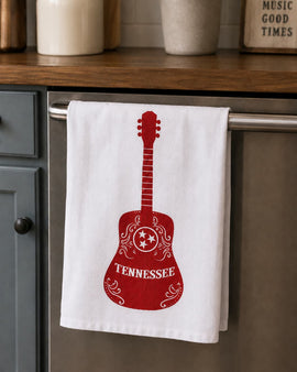 White towel with red guitar design hanging on a kitchen cabinet handle.